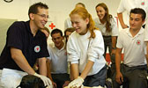 Foto: Eine Schülergruppe übt die Herz-Lungen-Wiederbelebung unter Anleitung eines Rotkreuz Mitarbeiters. Dieses Foto ist gleichzeitig ein Link und führt Sie zu der Unterseite: Junge Bereitschaft.